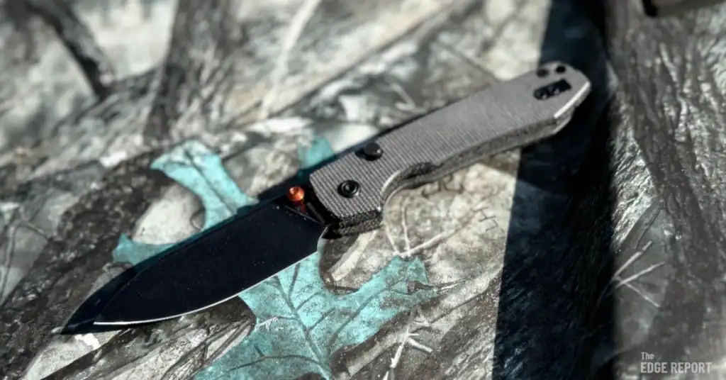 Dark brown micarta scales, black stone washed blade and orange thumb stud Vosteed Raccoon laying open on the hood of a Side by Side with Real Tree camo wrap