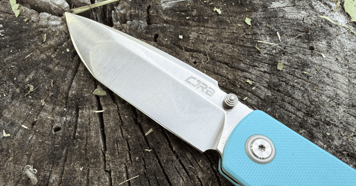 Macro shot of the CJRB Nova blade showing off the compound grind and the CJRB logo laser etched next to the thumb stud.
