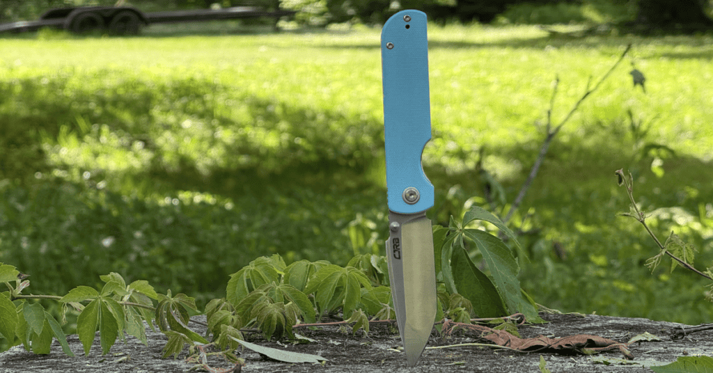 CJRB Nova in baby blue G10 with tip stuck into a log.